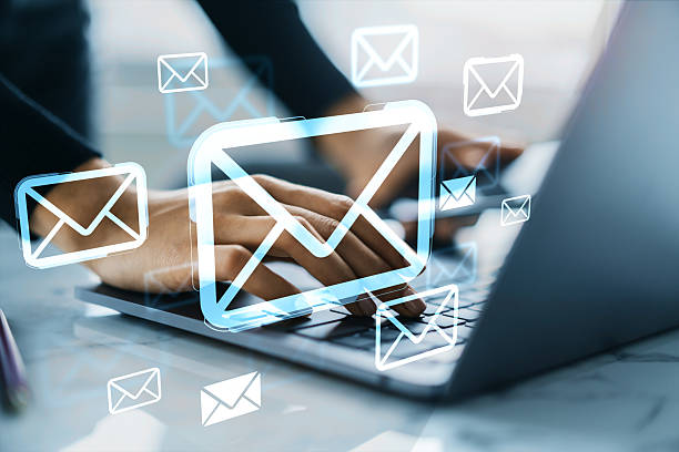 Person typing on laptop with glowing email icons overlaid, modern style, on blurred desktop background, concept of digital communication and messaging