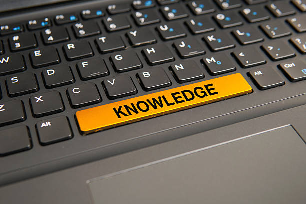 Close up of a computer keyboard with a yellow knowledge key, representing learning, expertise, information sharing, education, intellectual growth, and professional development concepts.