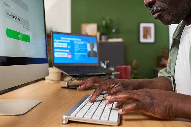 Close up of African American senior man and Caucasian middle aged woman learning online at home, using computer and laptop. Supporting digital skills training, lifelong education marketing