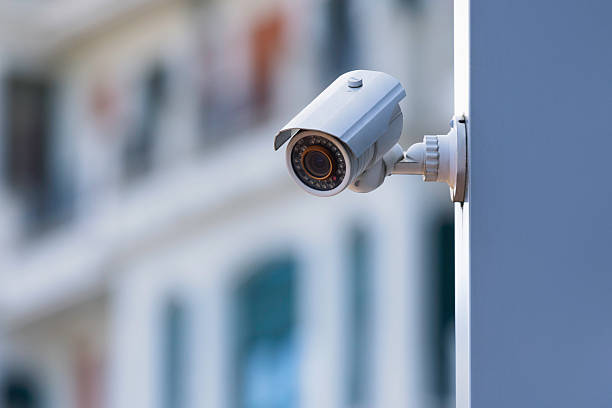 An infrared security camera on a building facade above a city street.