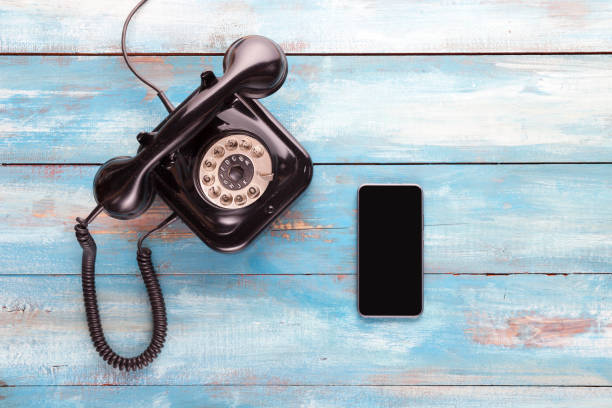 Old telephone and mobile phone on a blue wooden board